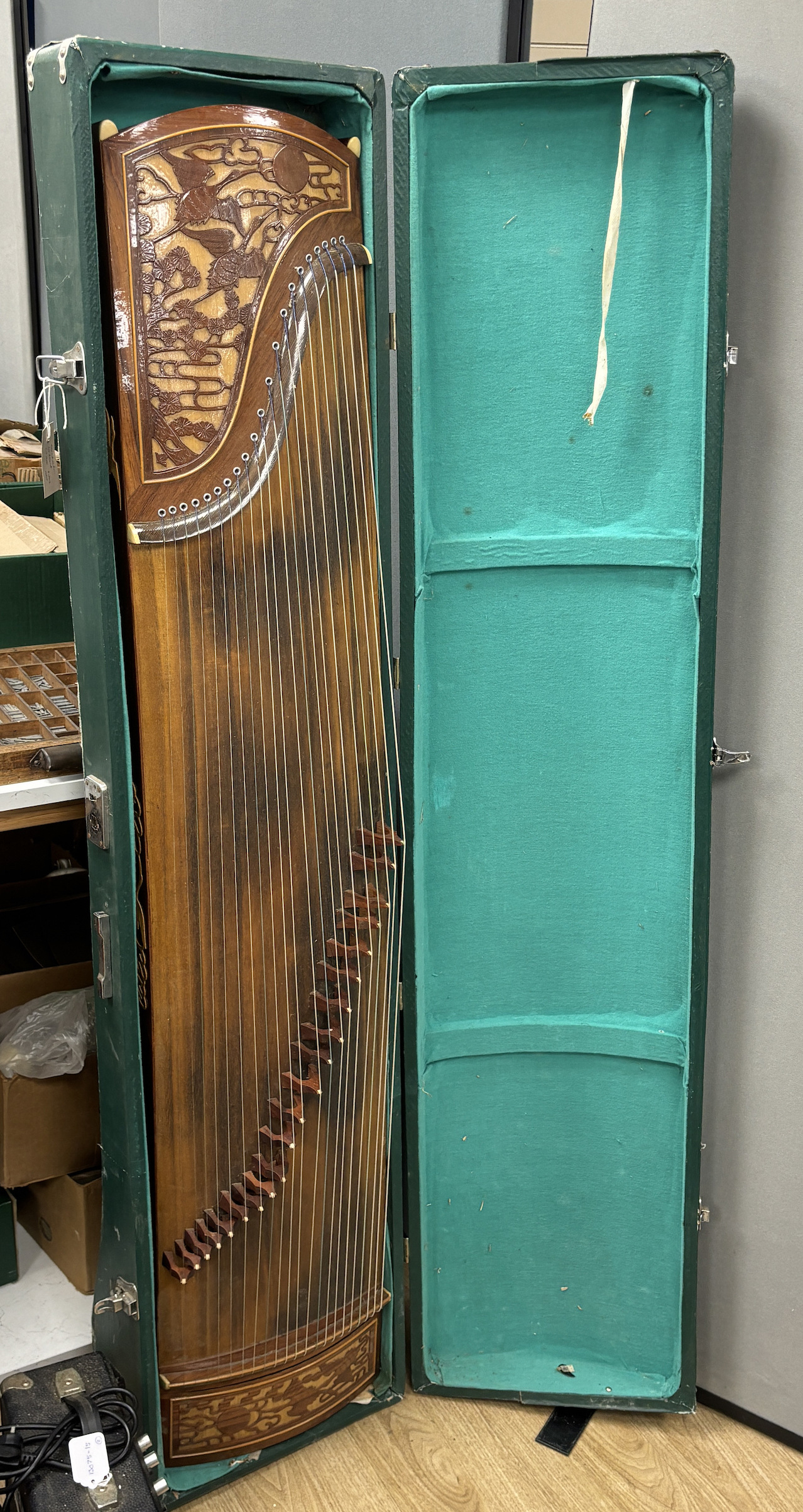 A cased Chinese Guzheng zither harp, hardwood body with blind fretwork decorative panel of birds and trees, with 21 strings, in fitted hard case, 163cm long